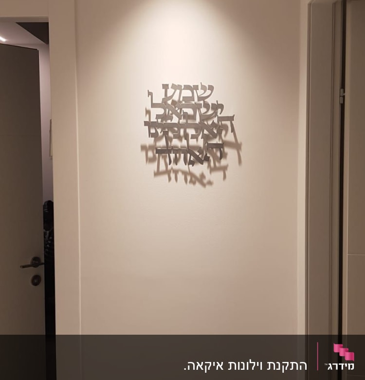 קיר עם שלט מתכת בעברית מואר בתאורה עליונה